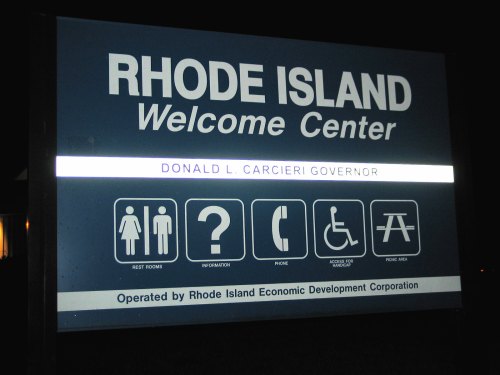 Sign for the Rhode Island Welcome Center featuring amenities like restrooms, information, and accessibility options.