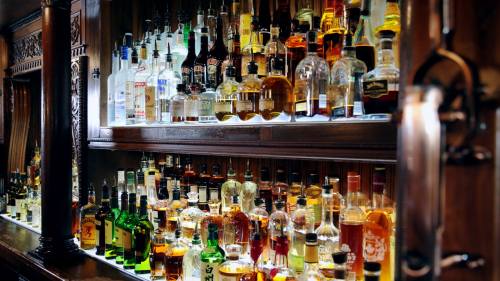 A well-stocked bar featuring a variety of liquor bottles displayed on wooden shelves.