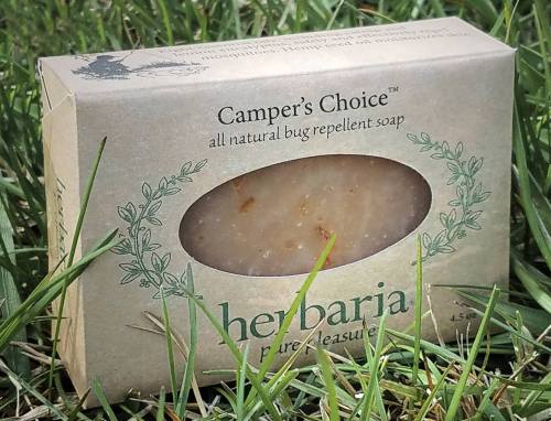 A box of all-natural bug repellent soap labeled "Camper's Choice" resting on green grass.