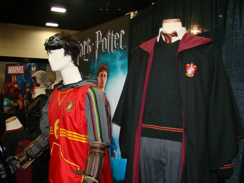 Display of Harry Potter-themed costumes, including a Quidditch jersey and a Hogwarts robe, at a convention.
