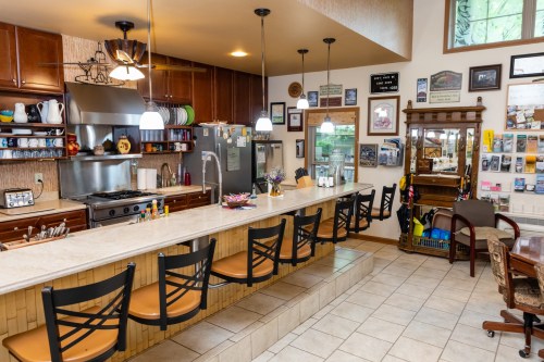 A cozy kitchen with a bar counter, stools, and various decorations on the walls, showcasing a warm, inviting atmosphere.