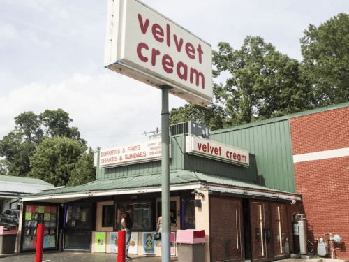 A retro-style ice cream shop named "Velvet Cream" with a sign, serving burgers, fries, shakes, and sundaes.