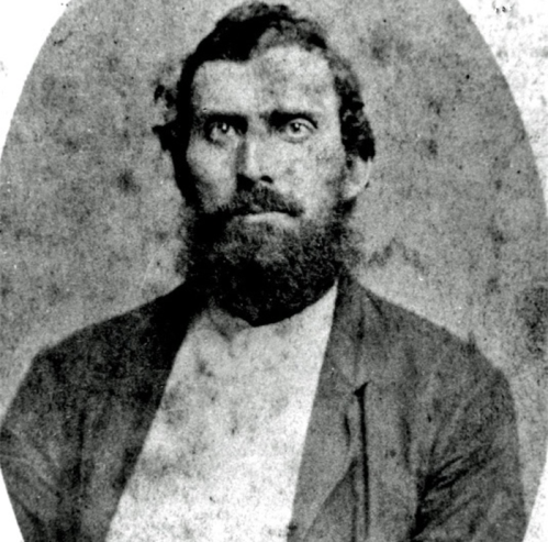 A vintage black-and-white portrait of a man with a beard, wearing a suit jacket and a plain shirt.