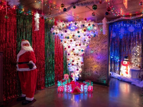 A festive room decorated with colorful lights, a Santa figure, and a unique tree made of lights and ornaments.