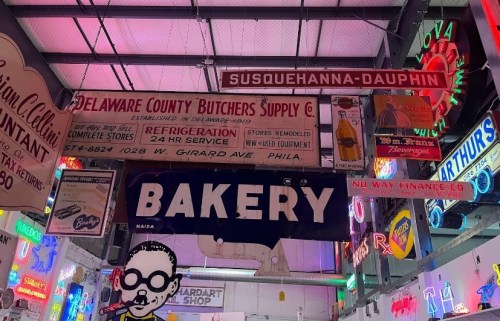 A vibrant display of vintage signs, including "Bakery" and "Delaware County Butchers Supply," in a colorful setting.
