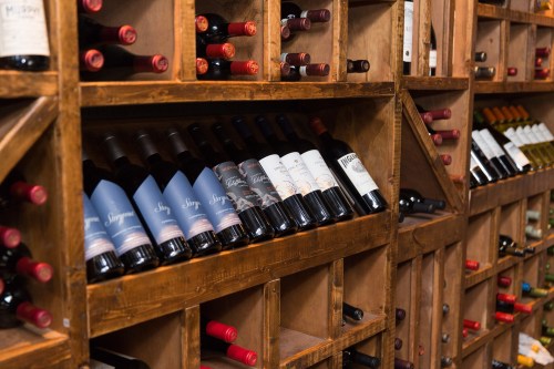 A wooden wine rack filled with various bottles of red and white wine, showcasing different labels and colors.