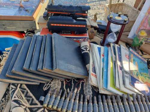 A collection of vintage books, magazines, and a toy train displayed on a patterned cloth with decorative items.