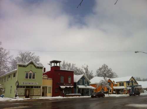 Colorful buildings line a snowy street under a cloudy sky, creating a charming winter scene.