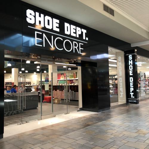 A storefront for "Shoe Dept. Encore" in a shopping mall, featuring large glass doors and a modern design.