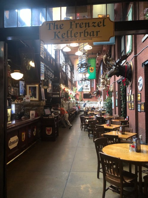 Interior of a cozy pub with wooden tables, decorative banners, and a bar area, creating a warm, inviting atmosphere.