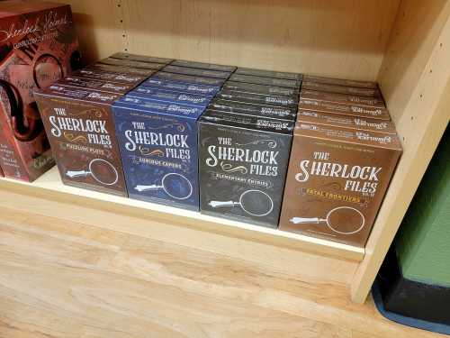 A shelf displaying several boxes of "The Sherlock Files" board games in various colors and designs.