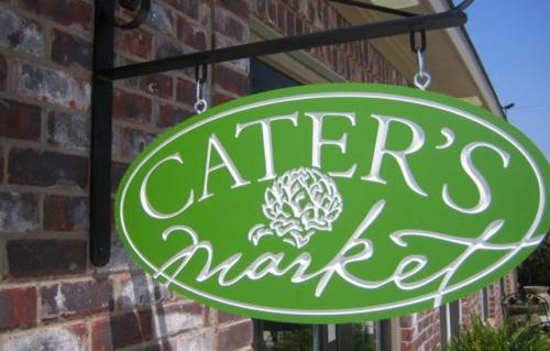 A green sign hanging from a brick wall reads "Cater's Market" in white cursive lettering.