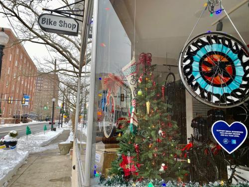 A festive bike shop window decorated for the holidays, featuring a Christmas tree and colorful ornaments.