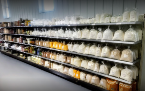 A neatly organized shelf displaying various bags of flour and other baking ingredients in a store.