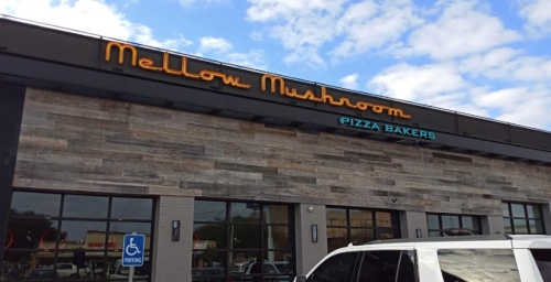 Exterior of Mellow Mushroom Pizza Bakers restaurant with a wooden facade and a blue sky in the background.