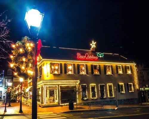 A festive building adorned with Christmas lights and a glowing "Macy's Christmas" sign at night.