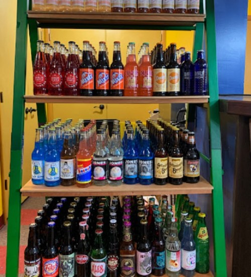 A colorful display of various soda bottles arranged on shelves in a store.