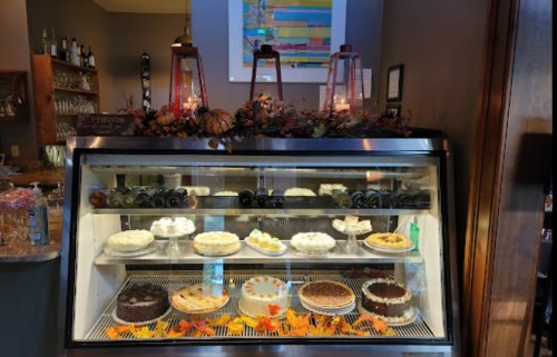 A display case filled with various cakes and desserts, decorated with autumn leaves and lanterns.