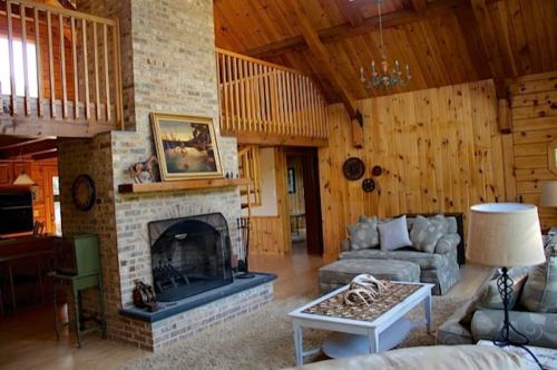 Cozy living room with a stone fireplace, wooden walls, and comfortable furniture in a rustic cabin setting.