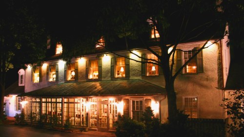 A charming building at night, illuminated windows, surrounded by trees, creating a warm and inviting atmosphere.