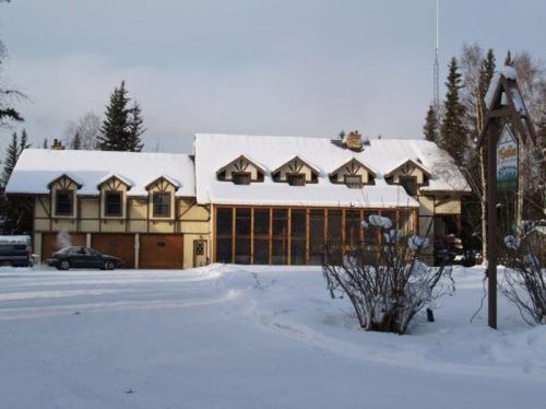 A large, snow-covered building with a wooden facade and multiple gabled windows, surrounded by a winter landscape.