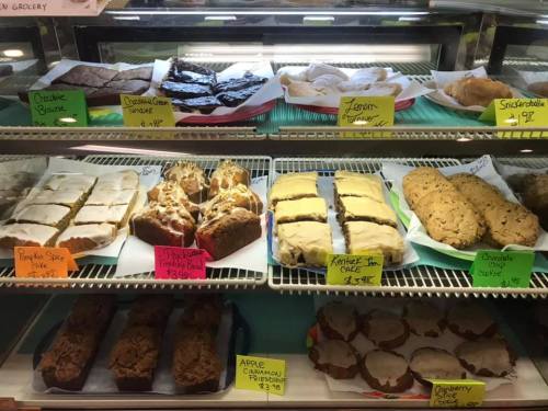 A display case filled with various baked goods, including brownies, lemon bars, and cookies, labeled with prices.