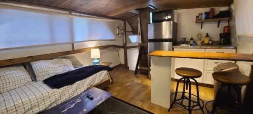 Cozy interior of a small living space featuring a sofa, kitchen area, and wooden accents.