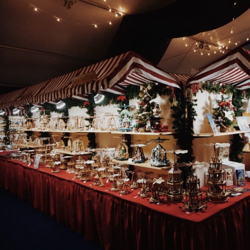 A festive market stall displaying various decorative items and ornaments, adorned with lights and greenery.