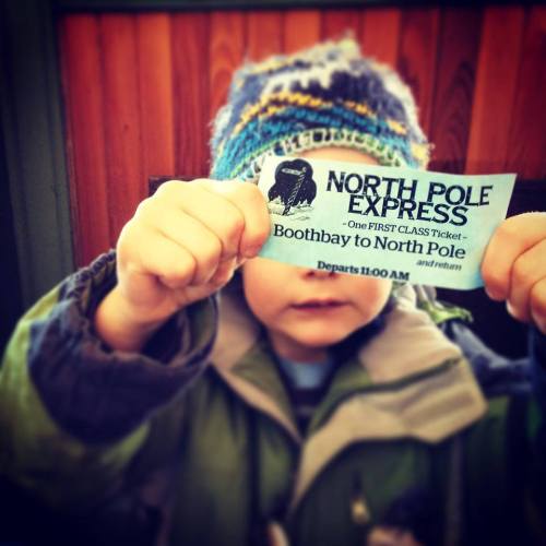 A child holds a ticket for the "North Pole Express," featuring a whimsical design and departure time.