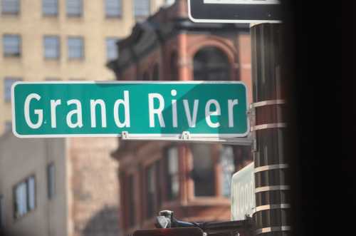 Street sign for Grand River, with buildings in the background.