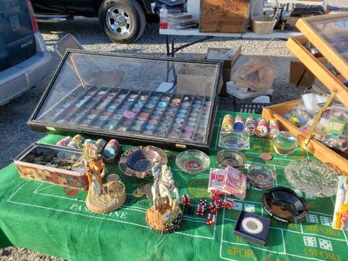 A table at a flea market displaying various collectibles, including figurines, dice, and colorful chips.