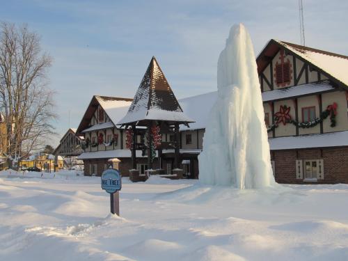 A snowy scene featuring a large ice formation in front of a decorated building with holiday wreaths.