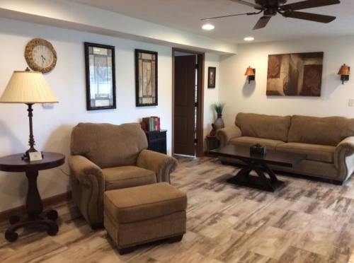 Cozy living room with two sofas, a lamp, a side table, and decorative wall art. Warm lighting and wooden flooring.