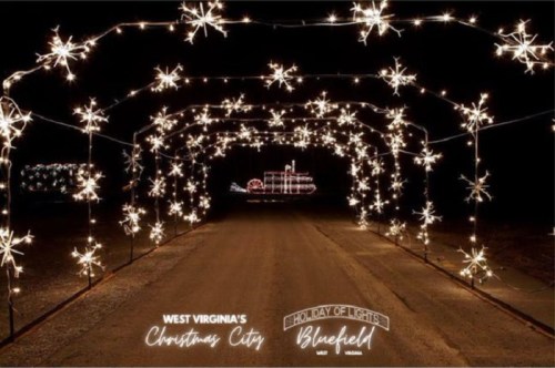A festive light display featuring star-shaped decorations along a dark pathway, promoting Bluefield's Holiday of Lights.