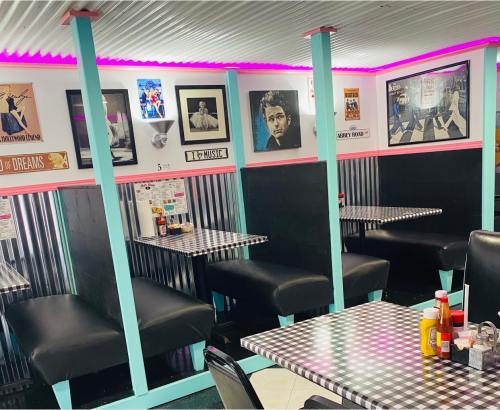 A retro diner interior with checkered tables, black booths, and colorful decor featuring music and movie posters.