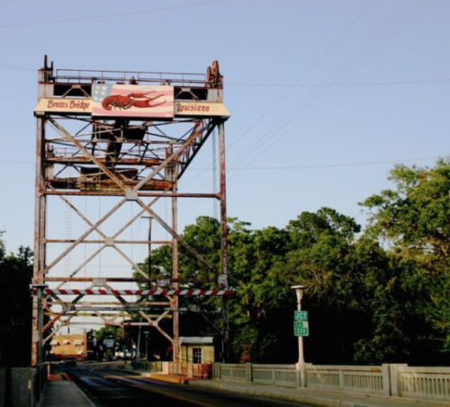 A drawbridge with a sign reading "Evan's Bridge" over a road, surrounded by trees and a clear sky.
