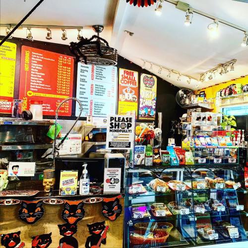 A colorful café interior with a menu board, snacks, and a display case filled with various items for sale.