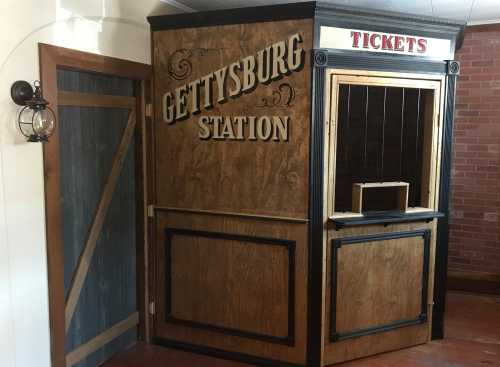 A vintage ticket booth with "Gettysburg Station" sign, featuring wooden panels and a small window for ticket sales.