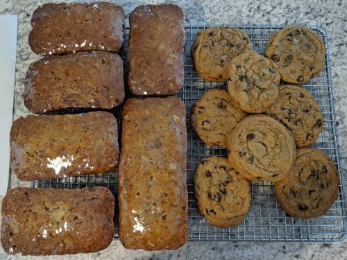 Freshly baked loaves of bread and chocolate chip cookies cooling on a wire rack.
