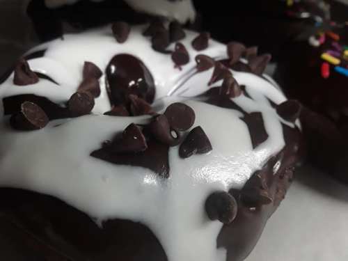 Close-up of a chocolate donut topped with white icing and chocolate chips.