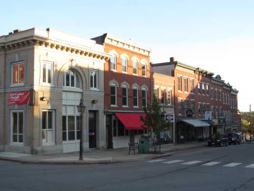 A quaint street scene featuring historic brick buildings, shops, and a clear sky in a small town.