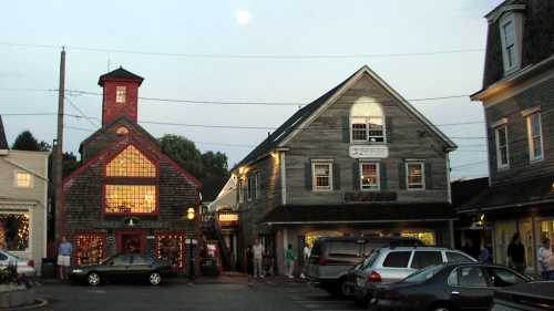 A quaint town square at dusk, featuring charming buildings, shops, and a full moon in the sky.