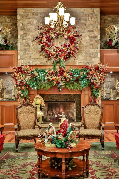 Cozy holiday living room with a stone fireplace, festive decorations, and elegant furniture.