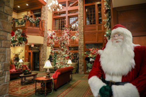 A festive lobby decorated for Christmas, featuring a large tree, garlands, and a Santa figure in the foreground.