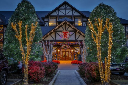 A beautifully decorated lodge entrance with festive lights, wreaths, and colorful flowers, set against a twilight sky.