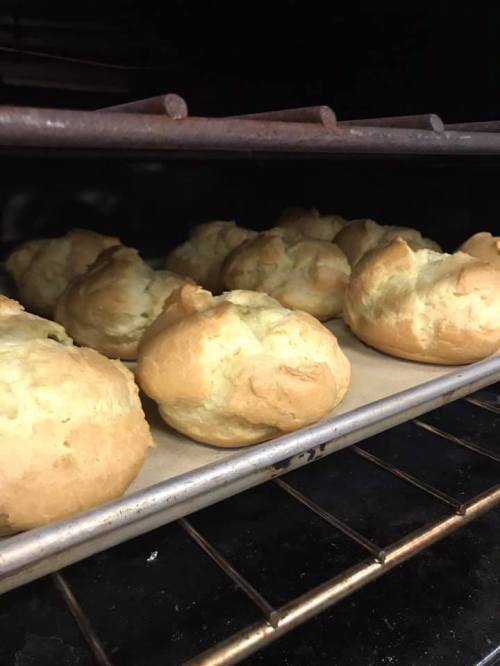 Golden-brown bread rolls baking on a tray in an oven, with a warm, inviting appearance.