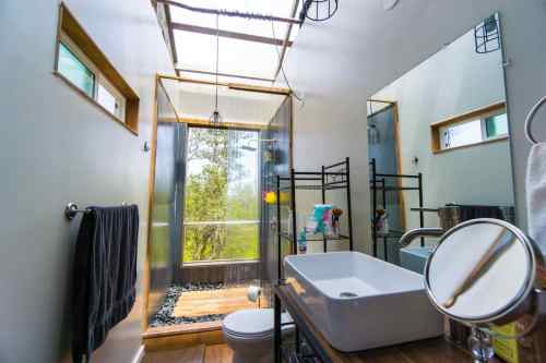 Modern bathroom with a skylight, large mirror, and a minimalist design featuring a freestanding sink and wooden accents.