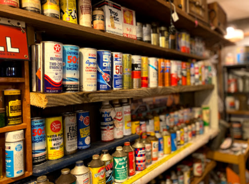 A shelf filled with vintage cans of oil and lubricants in various colors and designs.