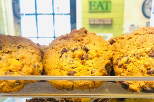 Close-up of freshly baked cookies with chocolate chips displayed in a glass case.