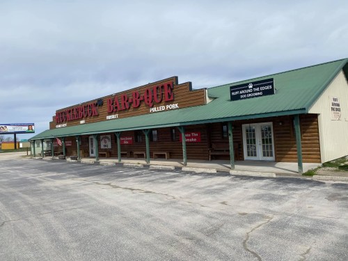 Exterior of a barbecue restaurant with a wooden facade, featuring signs for pulled pork and other menu items.